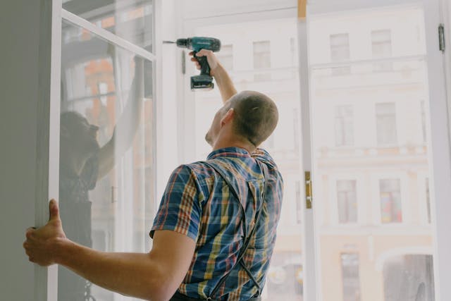 Person using a drill to install windows